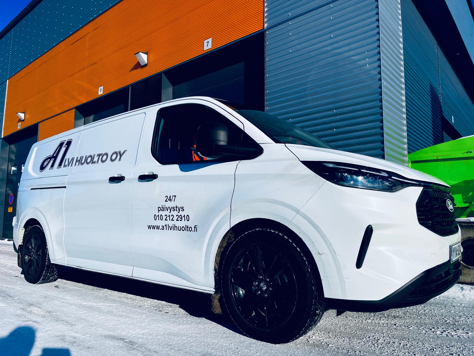 Valkoinen huoltoauto on pysäköity lumiselle alustalle modernin rakennuksen eteen, viitaten LVI-huoltopalveluihin.